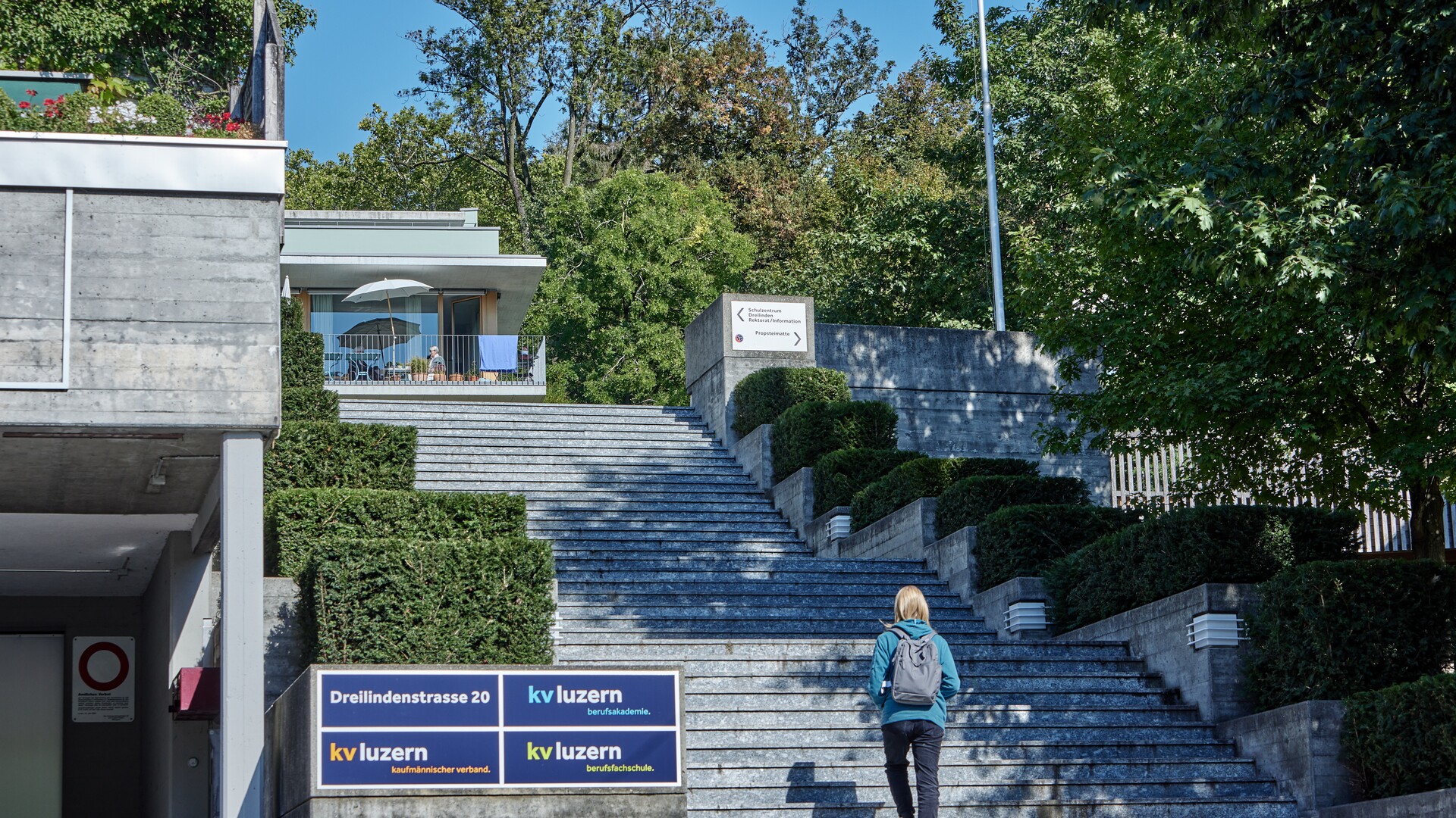 Eine Person geht eine Treppe vor einem Gebäude der KV Luzern hinauf.