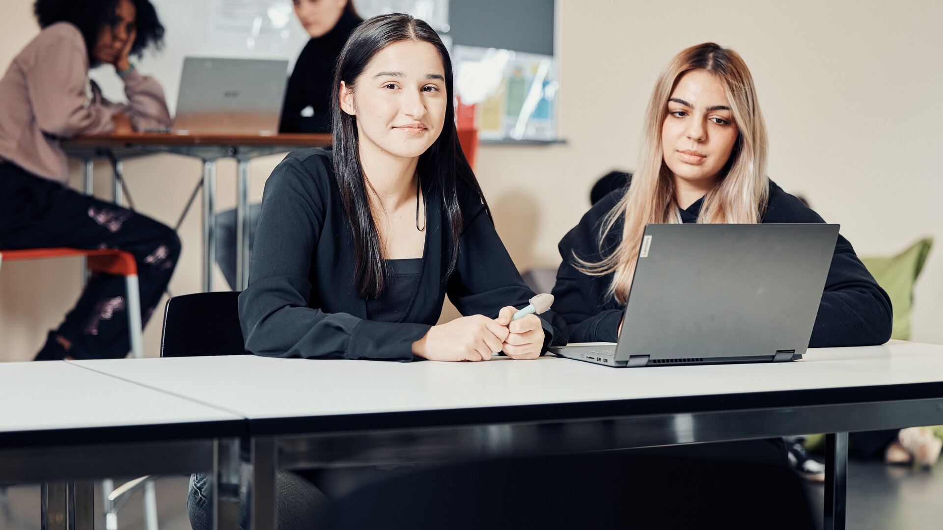 Zwei Frauen sitzen an einem Tisch und arbeiten gemeinsam an einem Laptop.